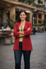 Woman in red blazer and jeans stands confidently in city next to her (magnetic phone mount) with arms crossed.